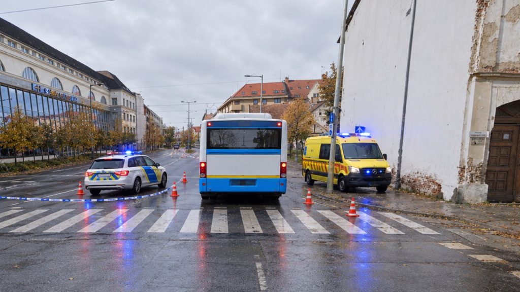 Baleseti helyszín a debreceni Széchenyi utca és Tisza István utca kereszteződésében: a busz hátulról a zebrán, mellette rendőrautó és mentőautó kék fénnyel, kordonszalag és bóják
