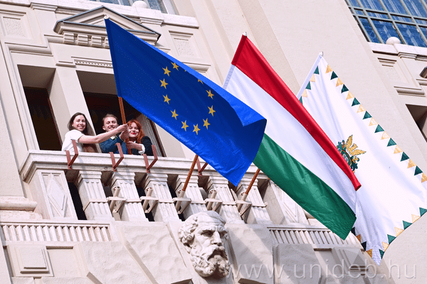 A Debreceni Egyetem főépülete előtt EU-zászló és útra kész hallgatók.