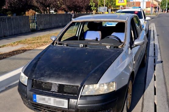 Szélvédő nélküli ezüst személyautó egy rendőrautó előtt Debrecenben, kitakart rendszámmal