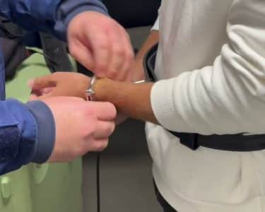 Rendőr megbilincseli egy férfi kezét, az arc nem látható