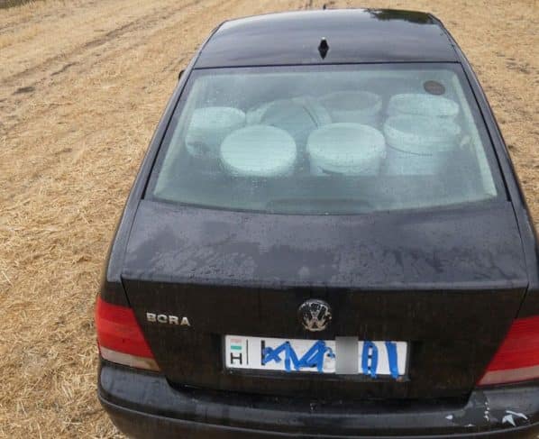 Fekete Volkswagen egy tarlón, a hátsó ülésen glettesvödrökkel, leragasztott rendszámmal